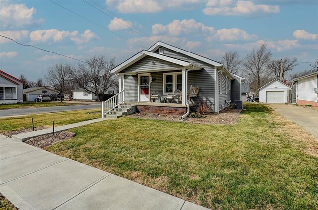 bungalow-style home featuring a front lawn, driveway, a porch, an outdoor structure, and a garage