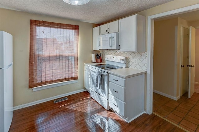 kitchen featuring white appliances, visible vents, dark wood finished floors, light countertops, and white cabinets