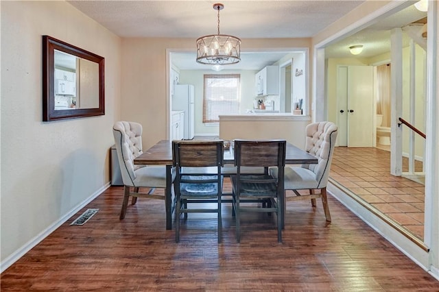 dining area with visible vents, baseboards, an inviting chandelier, dark wood-style floors, and a textured ceiling