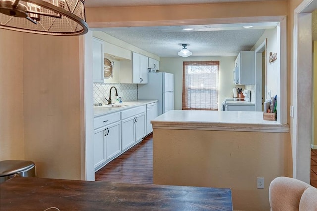 kitchen with a sink, range with electric cooktop, a textured ceiling, white cabinetry, and backsplash