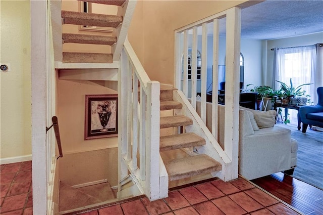 staircase featuring a textured ceiling and wood finished floors