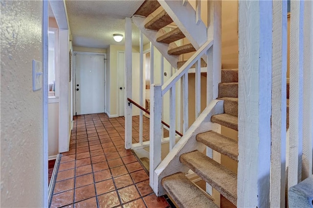 stairs with a textured wall, a textured ceiling, and tile patterned flooring