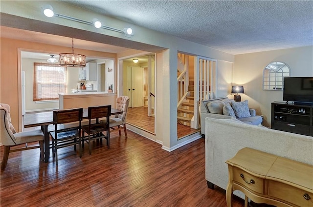 dining room with dark wood-style floors, plenty of natural light, a textured ceiling, and stairs