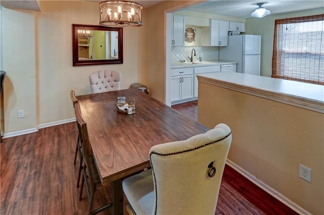 dining space with baseboards, a chandelier, and dark wood-style flooring