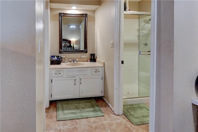 bathroom featuring vanity, baseboards, a stall shower, and tile patterned flooring