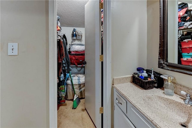 bathroom featuring a walk in closet, vanity, and a textured ceiling