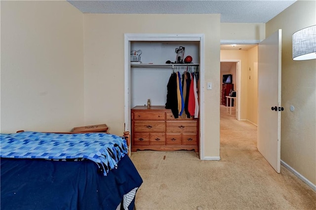 bedroom featuring a closet, carpet floors, a textured ceiling, and baseboards