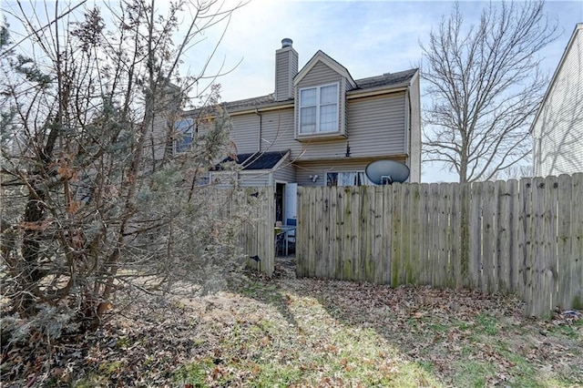 view of home's exterior featuring a chimney and fence