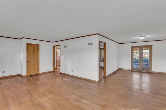 spare room with light wood-style flooring, baseboards, visible vents, and ornamental molding