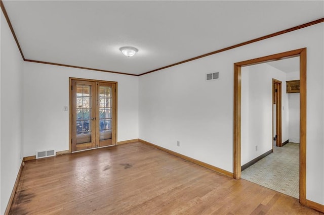 empty room featuring visible vents, wood finished floors, ornamental molding, and french doors