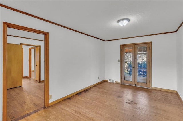 spare room with visible vents, french doors, light wood-type flooring, and ornamental molding