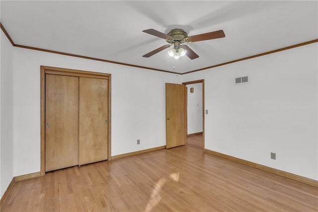 unfurnished bedroom featuring visible vents, light wood-style flooring, ornamental molding, a closet, and baseboards