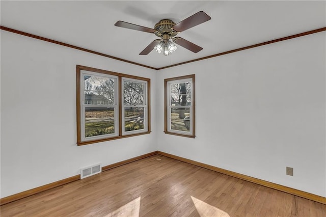 unfurnished room with visible vents, ornamental molding, wood finished floors, baseboards, and ceiling fan