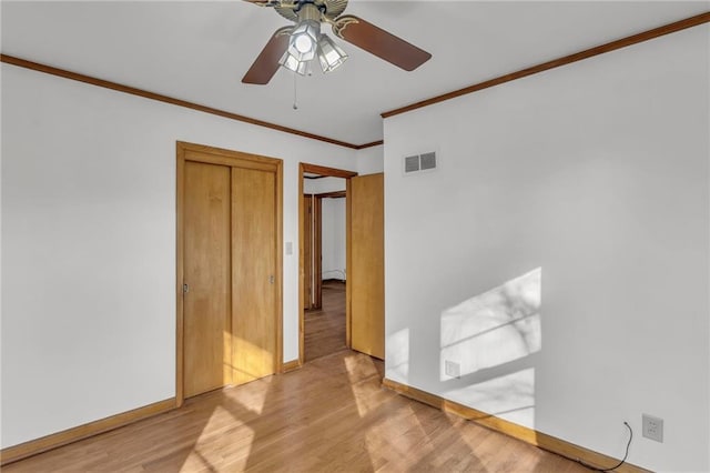 unfurnished room featuring a ceiling fan, wood finished floors, visible vents, baseboards, and crown molding