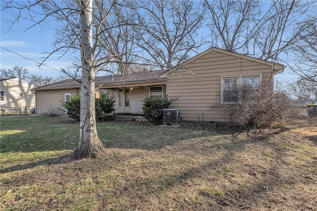 rear view of house with central AC unit, a lawn, covered porch, and fence