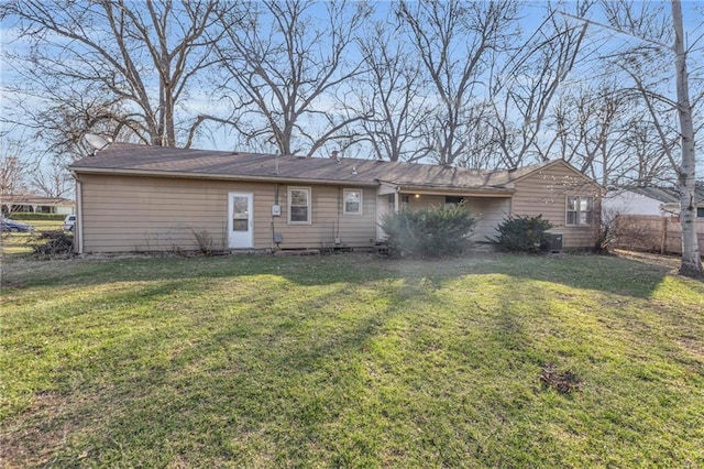 back of property featuring a lawn and fence