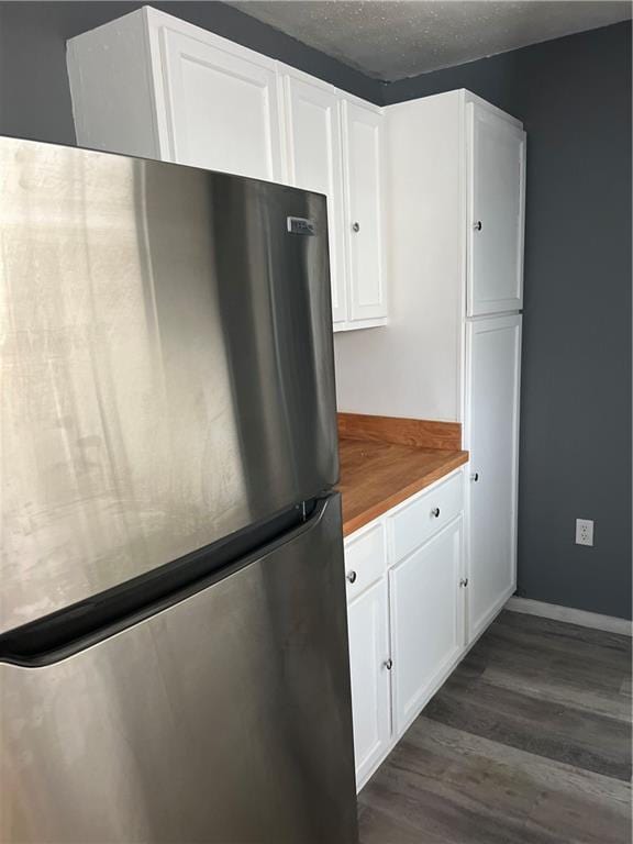 kitchen featuring white cabinets, dark wood-style flooring, freestanding refrigerator, and a textured ceiling