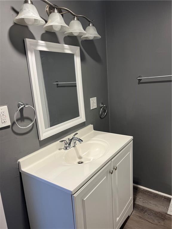 bathroom with baseboards, wood finished floors, and vanity