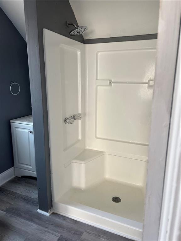 bathroom featuring baseboards, wood finished floors, a shower stall, and vaulted ceiling