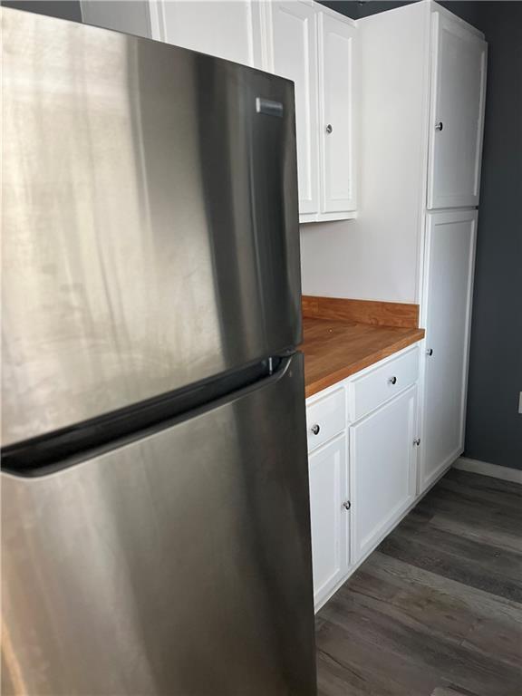 kitchen with white cabinetry, dark wood-style floors, freestanding refrigerator, and wood counters