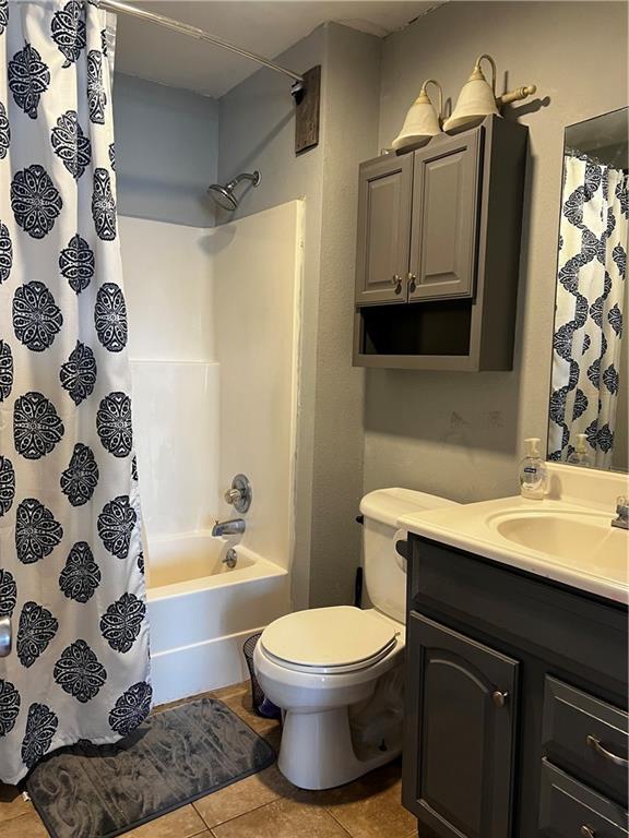 full bathroom featuring shower / bath combo with shower curtain, toilet, vanity, and tile patterned flooring