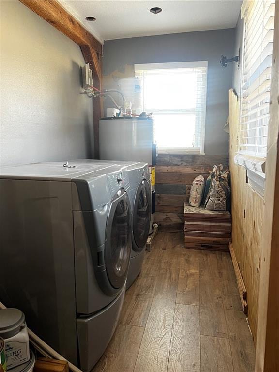 laundry room featuring washer and dryer, gas water heater, wood-type flooring, wood walls, and laundry area