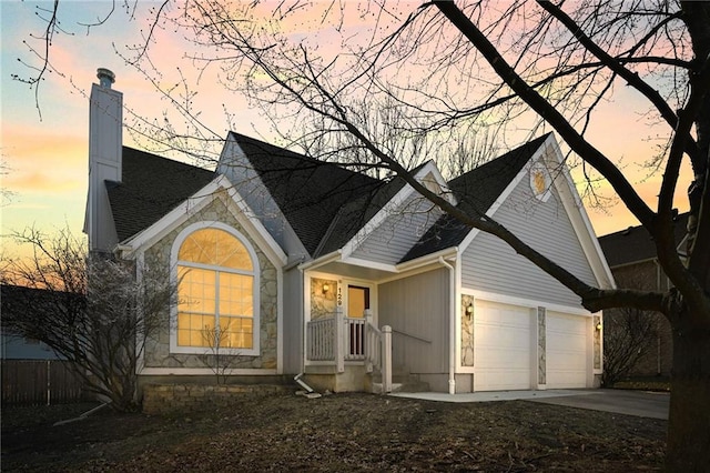 view of front of property with concrete driveway, a garage, stone siding, and a chimney