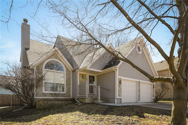 traditional-style home featuring fence, roof with shingles, concrete driveway, an attached garage, and a chimney