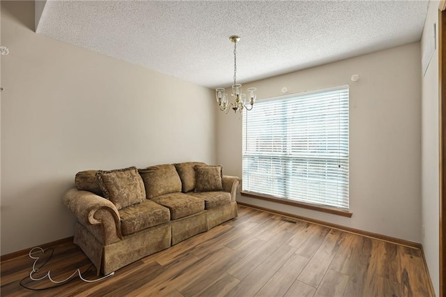 living area with a chandelier, a textured ceiling, visible vents, and wood finished floors