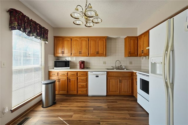 kitchen featuring visible vents, white appliances, brown cabinets, and dark wood finished floors