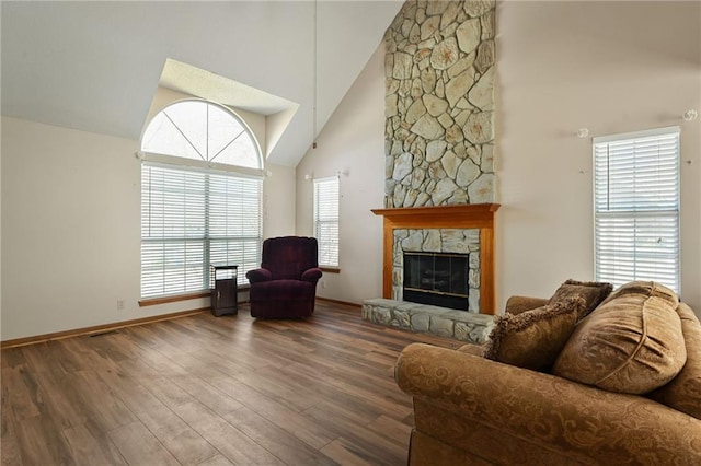 living area with baseboards, high vaulted ceiling, wood finished floors, and a fireplace