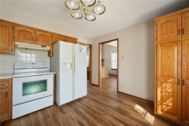 kitchen featuring under cabinet range hood, backsplash, dark wood-style floors, white appliances, and light countertops