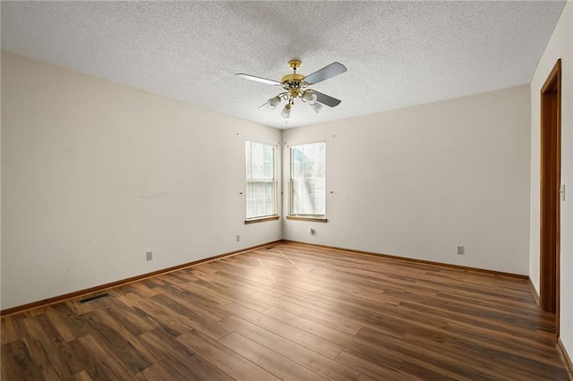 empty room featuring wood finished floors, baseboards, visible vents, ceiling fan, and a textured ceiling