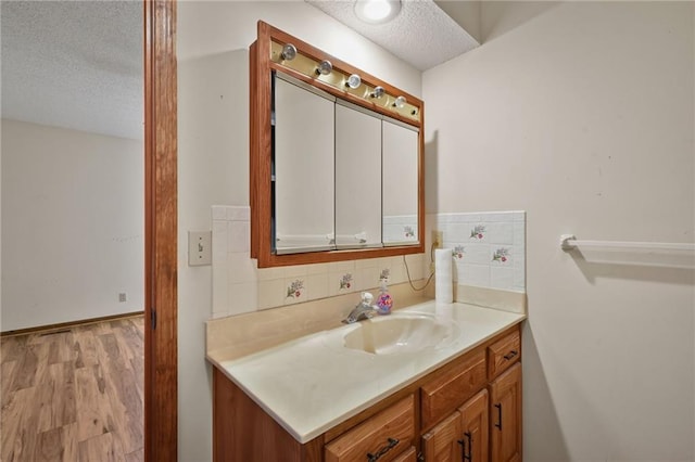 bathroom with decorative backsplash, wood finished floors, vanity, and a textured ceiling