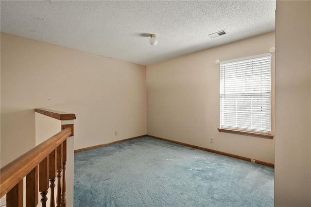 carpeted empty room featuring baseboards, visible vents, and a textured ceiling