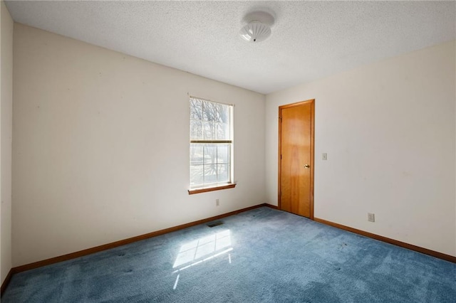 spare room with carpet, baseboards, and a textured ceiling