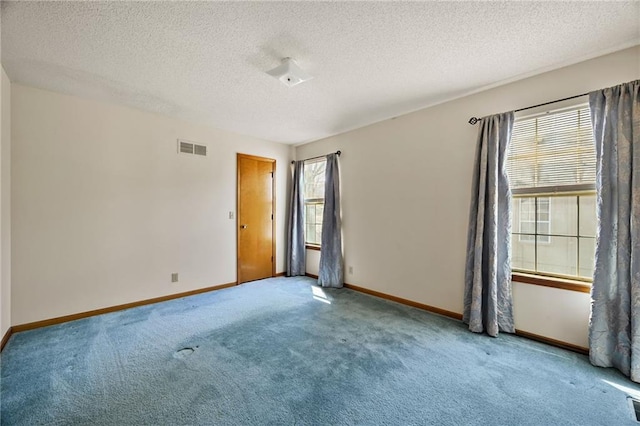 carpeted spare room featuring baseboards, visible vents, and a textured ceiling