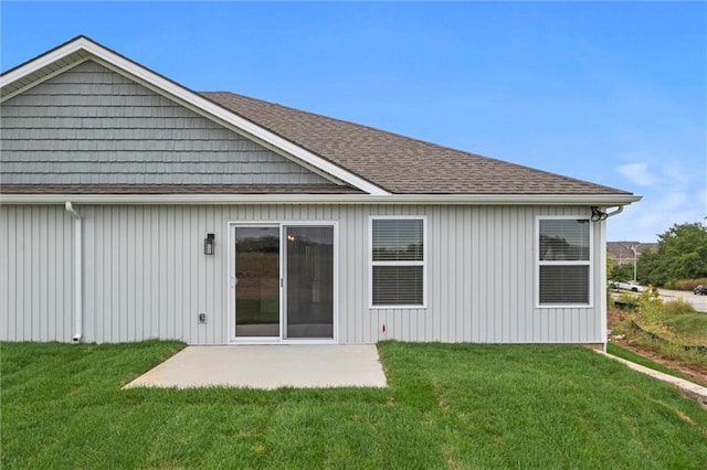 rear view of property with a patio area, a lawn, and roof with shingles