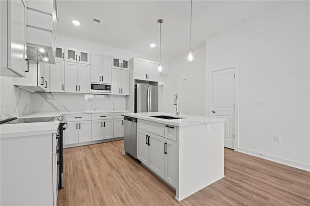 kitchen featuring white cabinetry, stainless steel appliances, light wood finished floors, and a sink