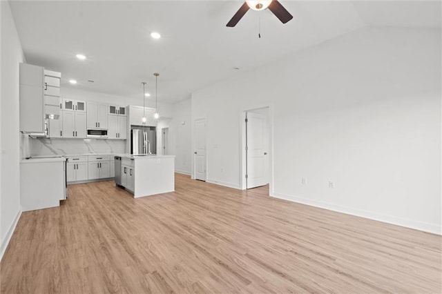 kitchen with light wood-style flooring, ceiling fan, stainless steel appliances, light countertops, and open floor plan