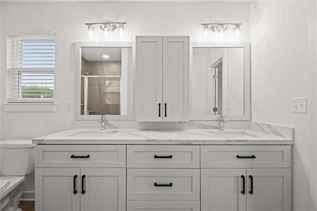 bathroom with a sink, toilet, double vanity, and a shower stall