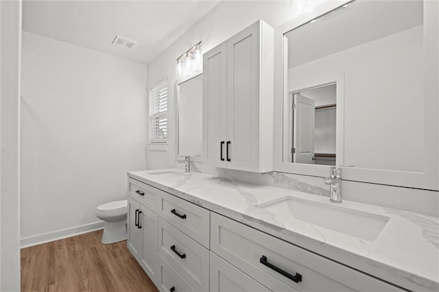 full bath with a sink, visible vents, toilet, and wood finished floors