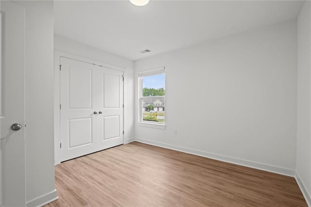 unfurnished bedroom with visible vents, baseboards, a closet, and light wood finished floors