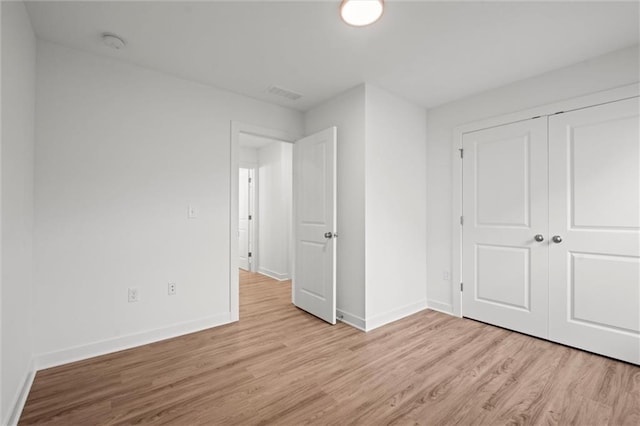 unfurnished bedroom featuring visible vents, baseboards, a closet, and light wood finished floors