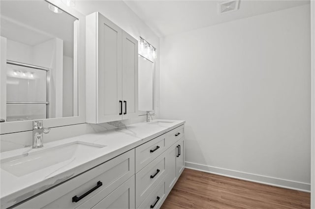 bathroom with a sink, visible vents, baseboards, and wood finished floors