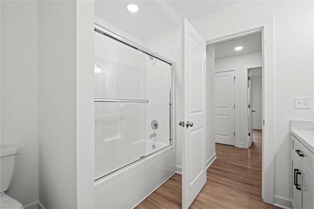 bathroom featuring vanity, wood finished floors, shower / bath combination with glass door, recessed lighting, and toilet