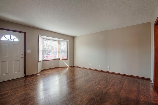 foyer entrance featuring wood finished floors, baseboards, and a textured ceiling