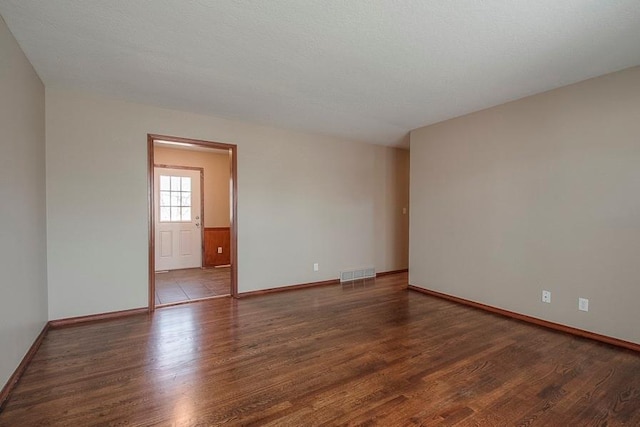 spare room featuring visible vents, baseboards, and wood finished floors