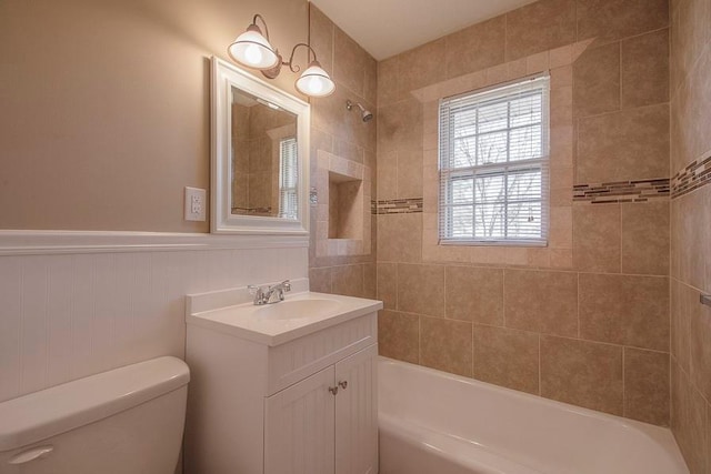 bathroom with a wainscoted wall, vanity, toilet, and shower / bathtub combination