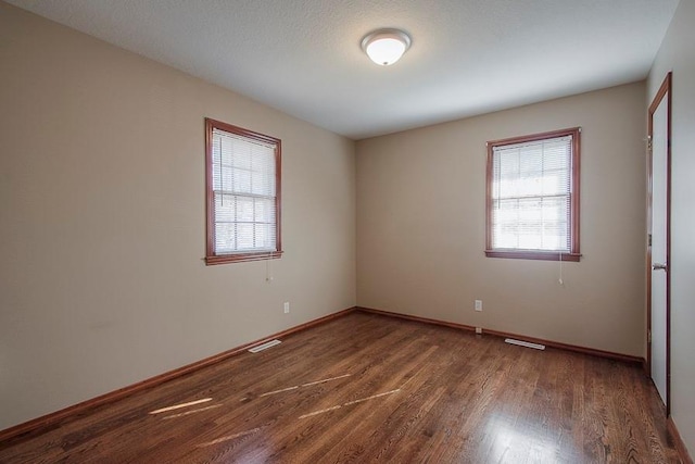 unfurnished room with visible vents, baseboards, and wood finished floors